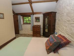 a bedroom with a bed and a cabinet and a window at Preseli Hills Cottage in Fishguard