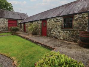 a stone house with a red door and a yard at Preseli Hills Cottage in Fishguard