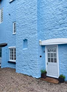 a blue building with a white door and two windows at Relaxing Riverside Retreat, Ross on Wye in Ross on Wye