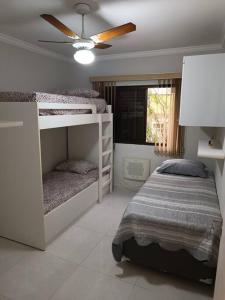 1 Schlafzimmer mit 2 Etagenbetten und einem Deckenventilator in der Unterkunft Apartamento em Enseada - Guarujá in Guarujá