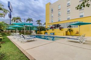 a pool at a hotel with chairs and umbrellas at City Express by Marriott Tuxtla Gutiérrez in Tuxtla Gutiérrez