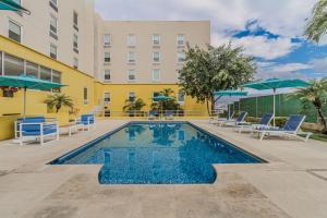 a pool at a hotel with chairs and umbrellas at City Express by Marriott Tuxtla Gutiérrez in Tuxtla Gutiérrez