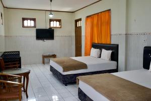 una camera d'albergo con due letti e una TV a schermo piatto di Garuda Setia Hotel a Kutoarjo