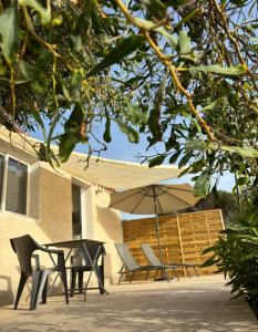 un patio avec une table, des chaises et un parasol dans l'établissement Appartement bord de mer 2 personnes, à Sagone