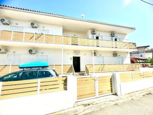 Ein Auto parkt vor einem Haus, auf dessen Dach ein Surfbrett liegt. in der Unterkunft Bed and Beach in Ýpsos