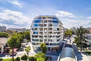 ein hohes weißes Gebäude mit Fenstern auf einer Stadtstraße in der Unterkunft HOT Main Square Newly Built Modern Apartment in Burgas City