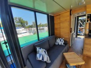 salon z kanapą i dużym oknem w obiekcie Domki pływające Houseboat4U, Mazury w mieście Ruciane-Nida