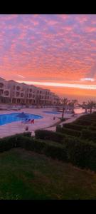 a sunset at a resort with a swimming pool at Lasirina palm beach for families only in Ain Sokhna +33 photos