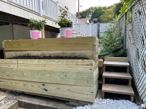 a wooden planter with two potted plants and stairs at Boston Single Family House - 19' Train to Back Bay in Boston