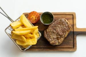 a steak and french fries on a tray with sauce at Aloft London Excel in London