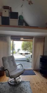 a white chair in a living room with a sliding glass door at Tuinhuis In je Element in Hoogeveen