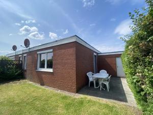 a brick house with a table and two chairs at Bungalow in Dornumersiel in Dornumersiel