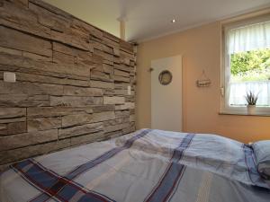 a bedroom with a stone wall and a bed at Bungalow in Dornumersiel in Dornumersiel
