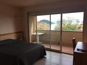 1 dormitorio con cama y vistas a un balcón en Hôtel restaurant le Ressac en Campomoro