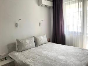 ein Schlafzimmer mit einem Bett mit weißer Bettwäsche und einem Fenster in der Unterkunft HOT Main Square Newly Built Modern Apartment in Burgas City
