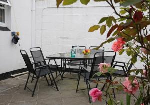 a table and chairs on a patio with flowers at Park View House Close to Central Park and Plymouth Argyle FC - Dogs welcome - Hosted by Absolute Accommodation Plymouth in Plymouth