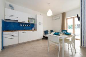una cucina con mobili bianchi, tavolo e sedie bianchi di Casa Vacanze Elvè a Paestum