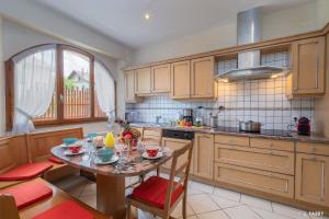 a kitchen with a table and chairs and a table and a window at Maison SAUTREAU Bout du Lac in Doussard