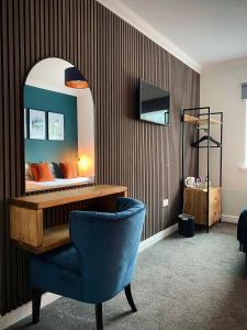 1 dormitorio con cama con espejo y silla azul en Lochside Guest House en Arrochar