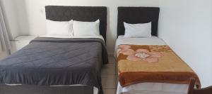 two beds sitting next to each other in a room at Hotel João Luzia in Villa Nova de Resende