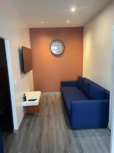 sala de estar con sofá azul y reloj en la pared en Escapade urbaine- Monchat- Lyon, en Lyon