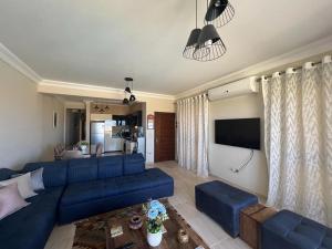 a living room with a blue couch and a tv at La Vista Bay North Coast Halafawy's Full Sea View لا فيستا باي الساحل الشمالي بيت الحلفاوي in Dawwār Ḩājj as Sayyid Rizq