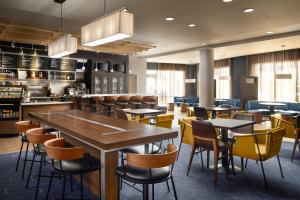 a restaurant with tables and chairs and a kitchen at Courtyard by Marriott Hammond in Hammond