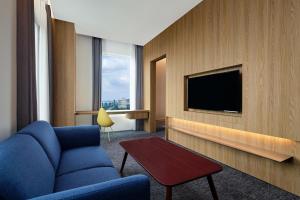 a hotel room with a blue couch and a tv at Aloft South Jakarta in Jakarta