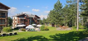 a large building with a yard with chairs and tables at Green Peaks Suite in Pirin Golf & County Club in Razlog