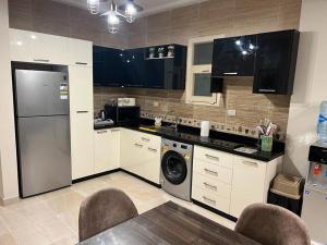 a kitchen with a refrigerator and a dishwasher at La Vista Bay North Coast Halafawy's Full Sea View لا فيستا باي الساحل الشمالي بيت الحلفاوي in Dawwār Ḩājj as Sayyid Rizq