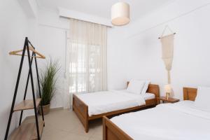 una stanza bianca con due letti e una finestra di MainAvenue Palm Seaside a Polykhrono