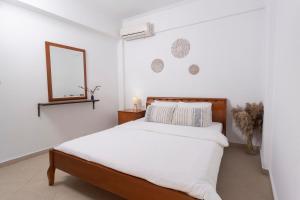 una camera da letto bianca con un letto e uno specchio di MainAvenue Palm Seaside a Polykhrono