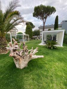 a tree stump sitting on the grass in a yard at Hotel Al Cigno in Lignano Sabbiadoro