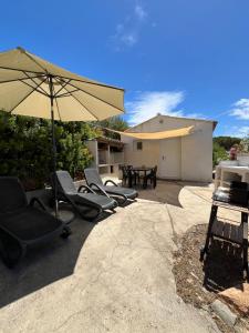 a group of chairs and an umbrella on a patio at Apparemment bord de mer 2 à 5 personnes in Sagone