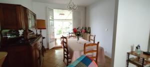 a dining room with a table with a vase of flowers on it at Maison de ville avec jardin in Thuir
