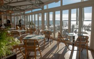 un restaurant avec des tables, des chaises et des fenêtres dans l'établissement Novotel Thalassa Ile d'Oléron, à Saint-Trojan-les-Bains