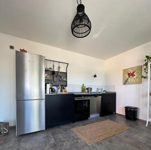 a kitchen with a stainless steel refrigerator and black cabinets at Eifeeloft - Eifel erleben in Neroth