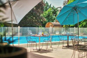 a table and chairs with umbrellas next to a pool at Kyriad Prestige Mulhouse - Basel in Sausheim