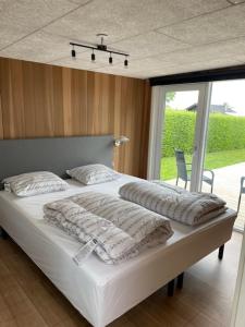 a bedroom with a large bed with white sheets and pillows at Coasthouse ved havet in Hadsund