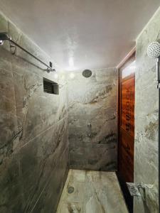Un baño con ducha con pared de piedra. en Anushttha Home Stay, en Faizābād