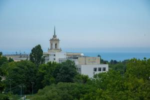 a white building with a clock tower on top of trees at VARNA SEA VIEW Apartment in Varna City