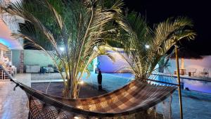 a hammock between two palm trees next to a pool at @BeachHouseItamaraca in Itamaracá +8 photos
