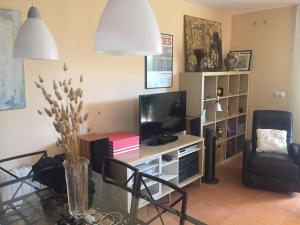 ein Wohnzimmer mit Fernseher und Tisch mit Stühlen in der Unterkunft Agradable adosado con piscina y jardín in Canet d'en Berenguer