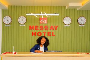 una mujer sentada en un escritorio en una habitación con relojes en Messay Hotel en Addis Abeba