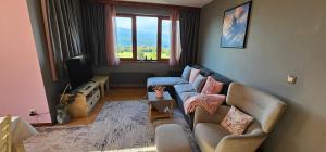 a living room with a couch and a tv at Green Peaks Suite in Pirin Golf & County Club in Razlog