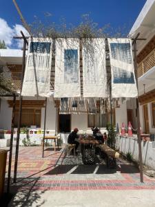 two people sitting at a table in front of a building at Rumi Cafe and Stay in Leh