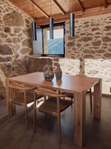 a wooden table in a room with a stone wall at Casiñas do Sil in Cristosende