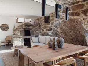 a dining room with a table and a stone wall at Casiñas do Sil in Cristosende