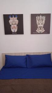 a bed with blue sheets and two pictures on the wall at Sole Urbano in Messina