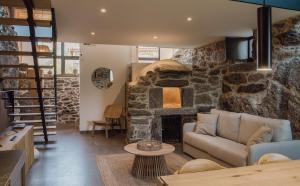 uma sala de estar com uma lareira de pedra e um sofá em Casiñas do Sil em Cristosende